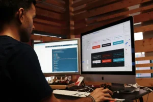 Designer travaillant sur l'interface d'un site web professionnel sur deux écrans